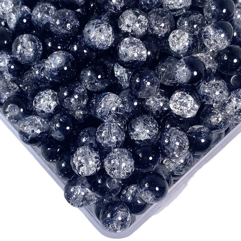 Top-down view of black crackle glass round beads in a clear plastic container