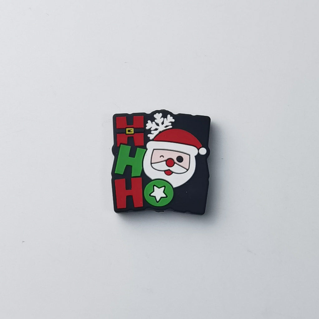 Square black silicone focal bead with red and green 'HO HO' lettering, Santa Claus face, snowflake and star