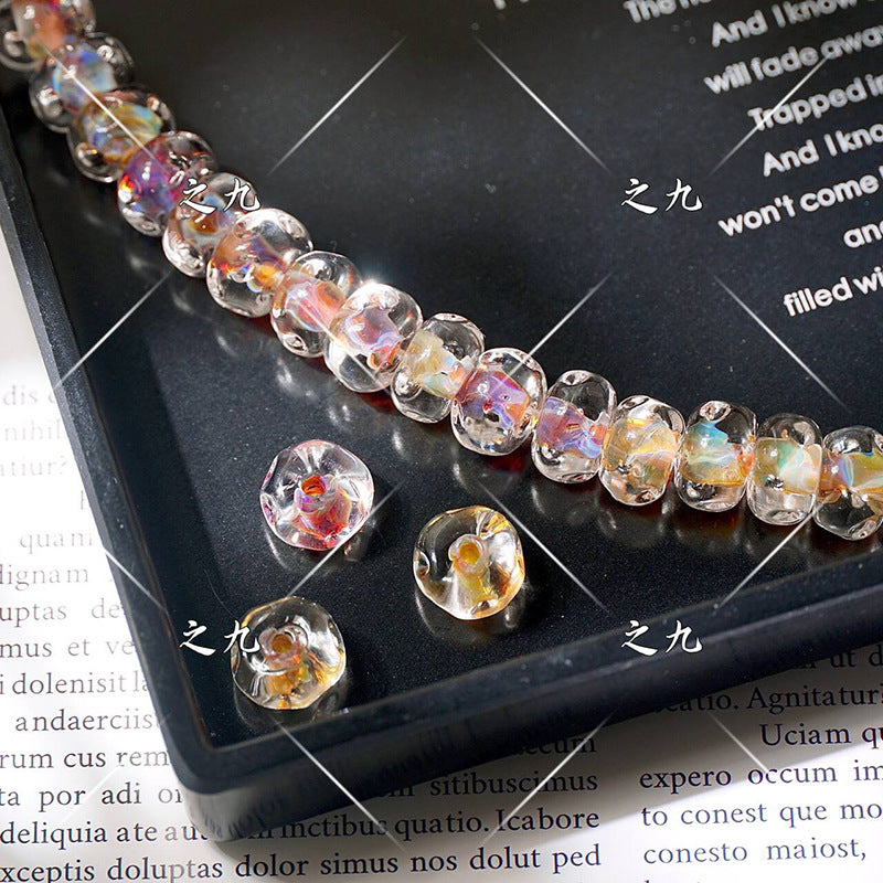 Clear lampwork beads with colorful iridescent inclusions on a black tray, loose beads