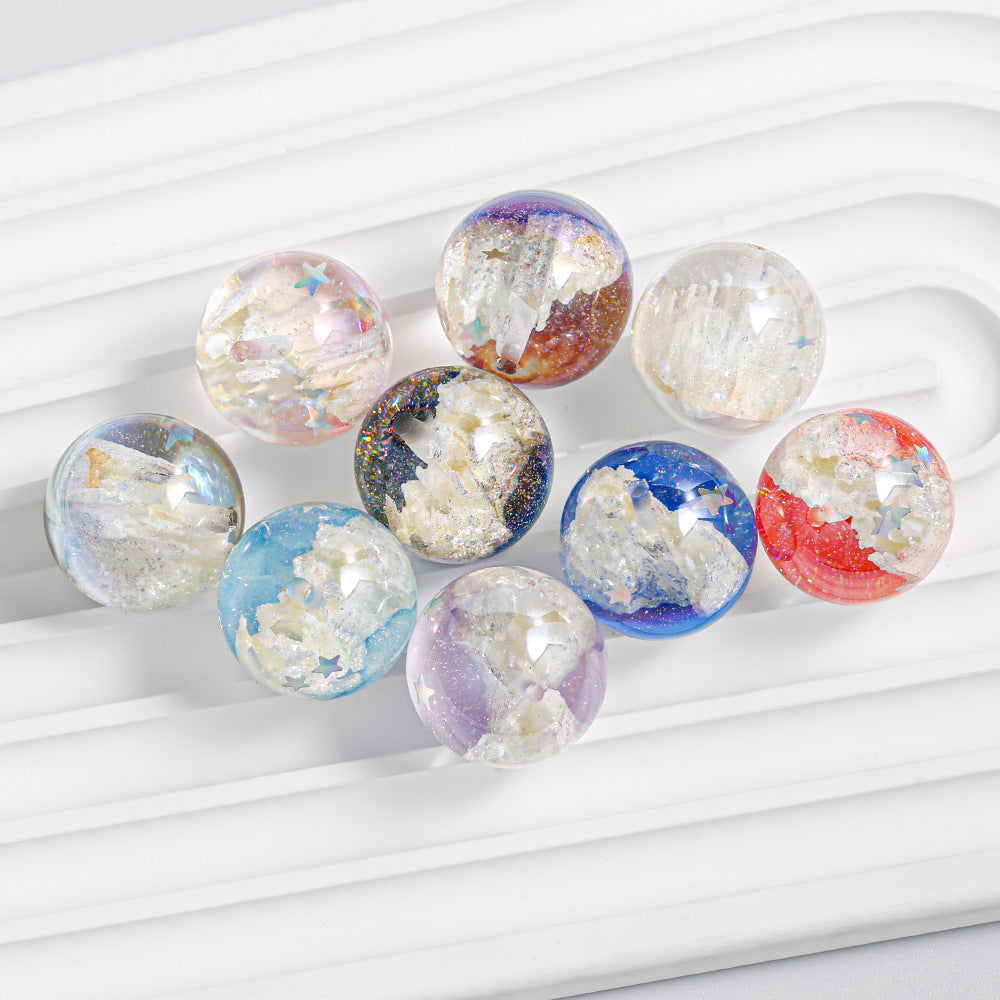 Nine round, iridescent resin beads filled with glitter and foil flakes, arranged on a white ribbed surface.