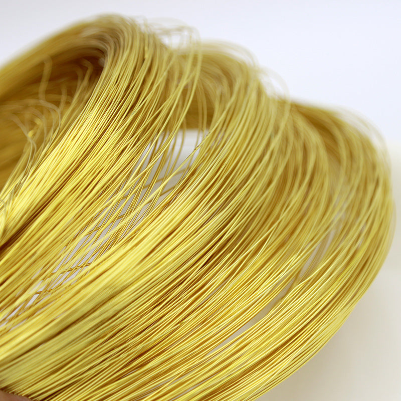 A close-up of a coiled bundle of thin, bright yellow-gold metallic wires on a plain white background.