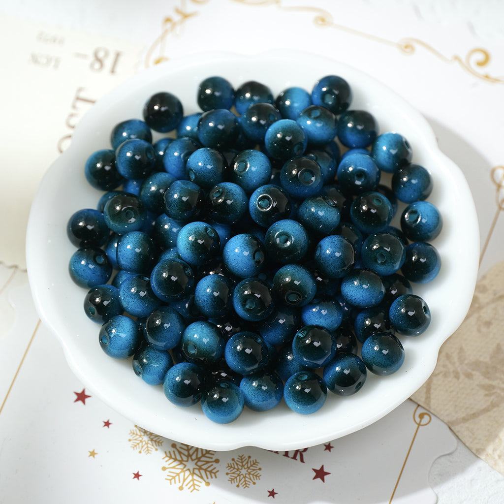 Glossy solid blue round glass beads in a white bowl