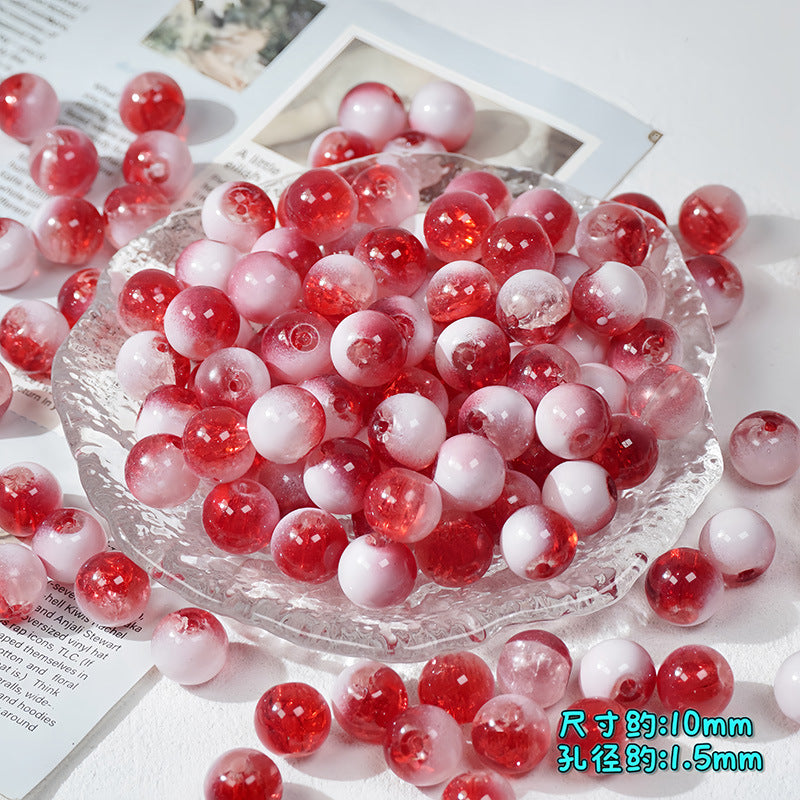 Red and white ice-crackle glass beads piled in a clear textured glass bowl with scattered beads