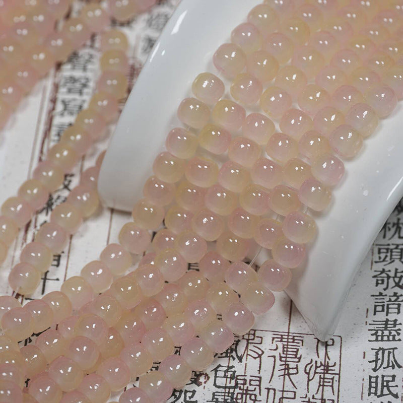 Pale pink translucent round bead strands over a white ceramic stand on printed paper with Chinese characters