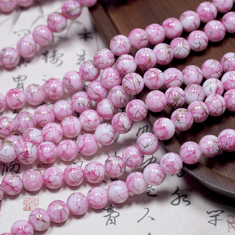 Pink and white marbled porcelain beads with gold veins on calligraphy paper