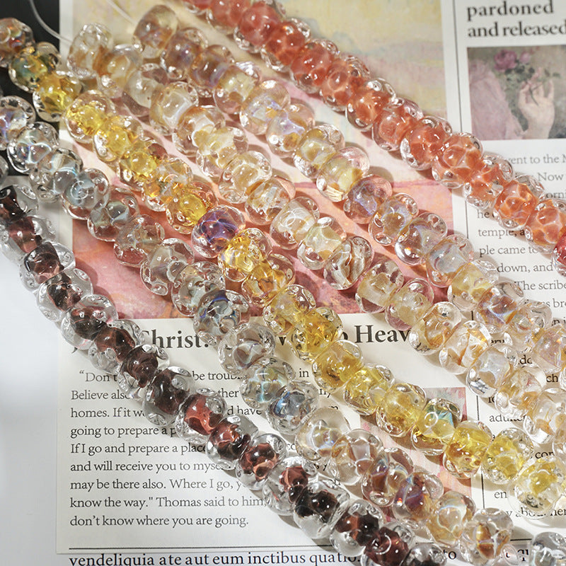 Strands of translucent water-ripple lampwork glass beads in yellow, orange, pink, purple and brown on printed pages