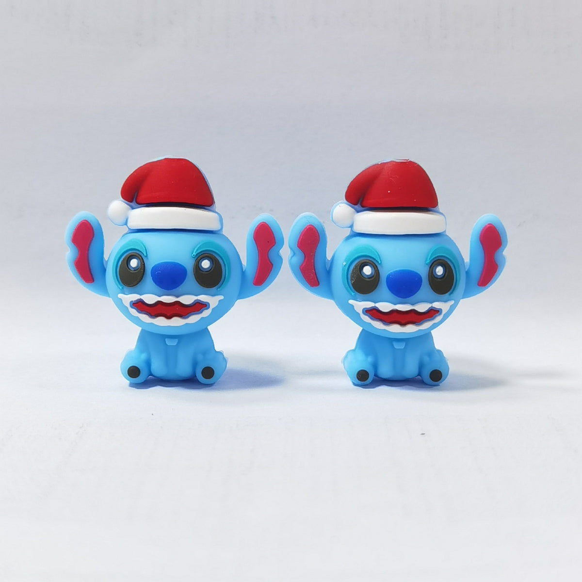 Two blue cartoon character silicone focal beads wearing red Santa hats