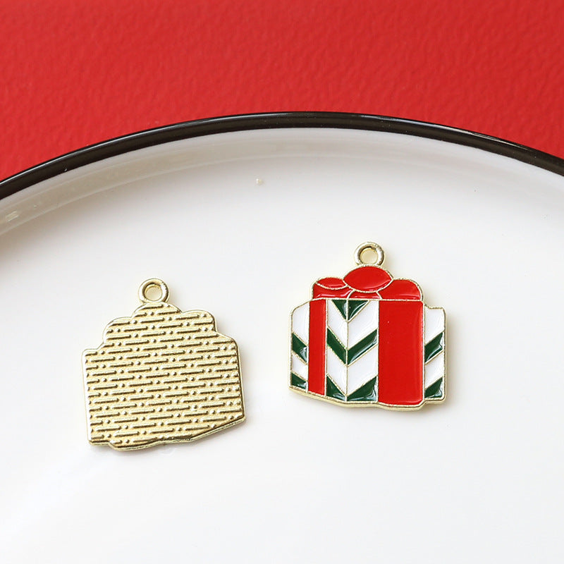 Two small gift-themed enamel alloy charms on white plate with red background