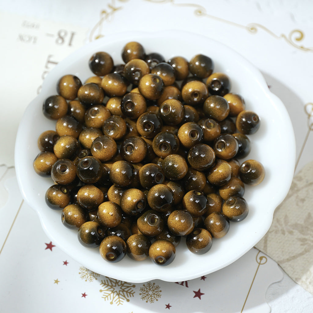 Round glossy brown and gold tiger's eye glass beads in a white bowl