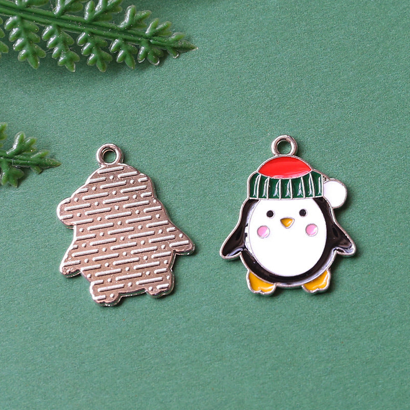 Two Christmas-themed metal charms on textured green background, silver bell