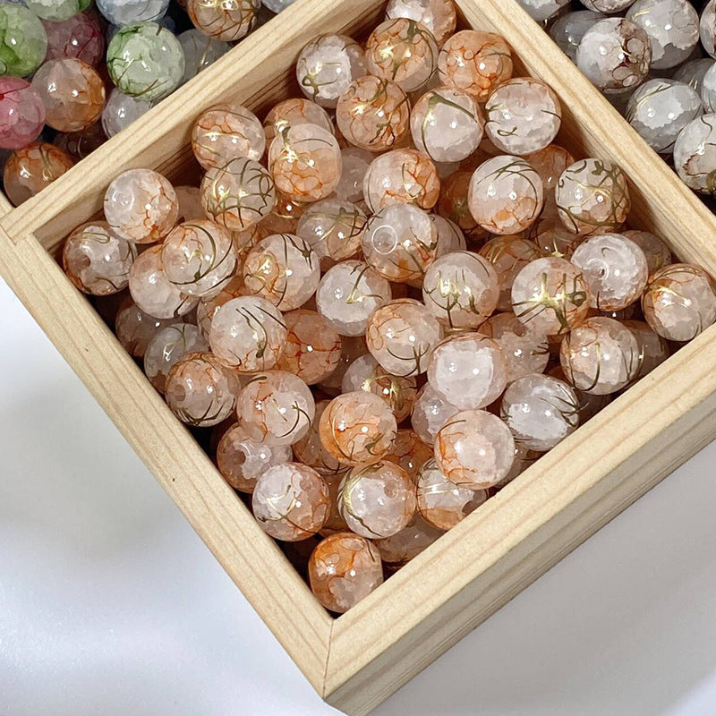 Orange crackle glass beads with gold-silk veins in a wooden tray