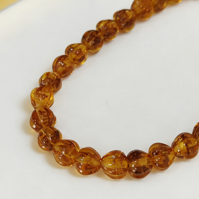 Close-up of translucent amber lantern glass beads on a white background