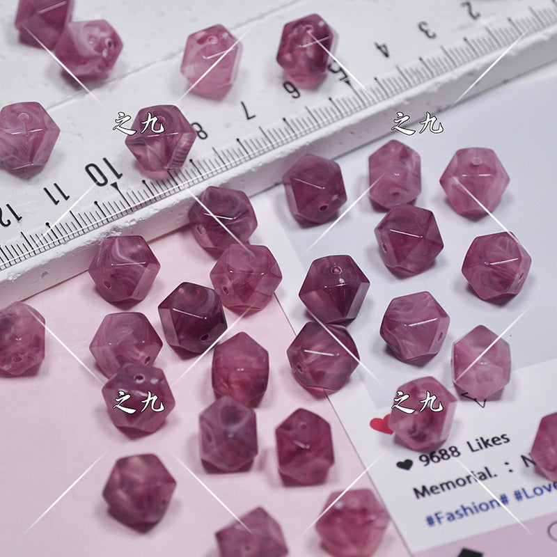 Faceted pink beads scattered on a white surface next to a ruler for scale