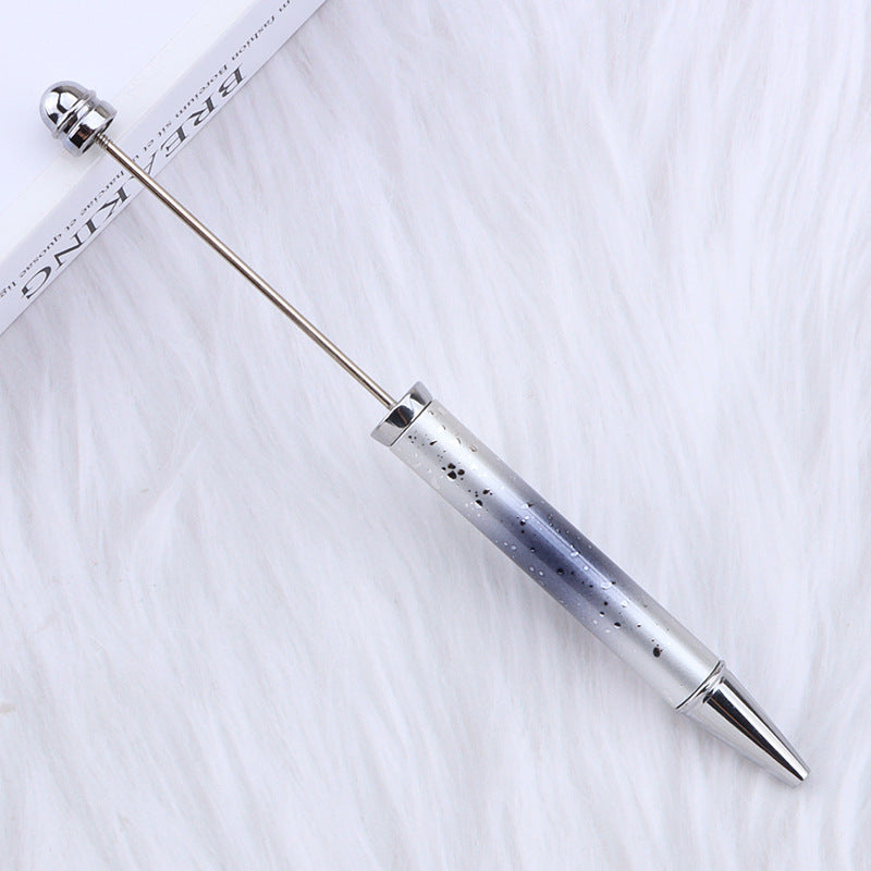 Silver ombre beadable pen with gradient design on a white fabric background.