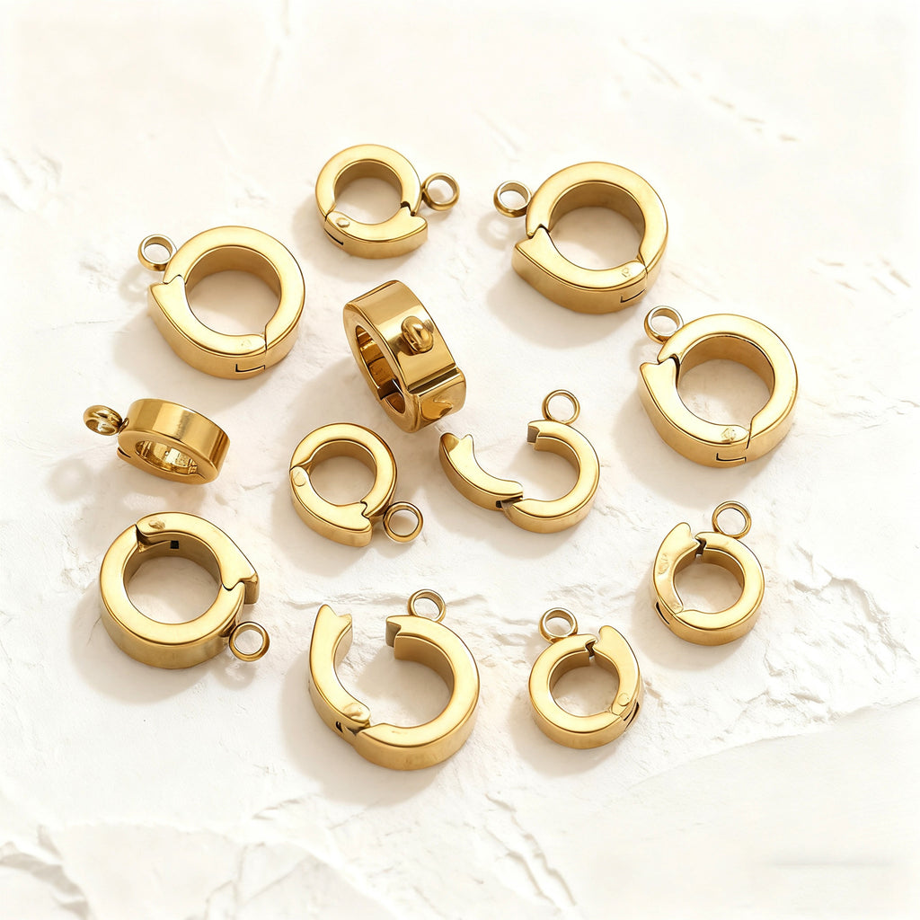 Small gold open-ring connector clasps scattered on a white background