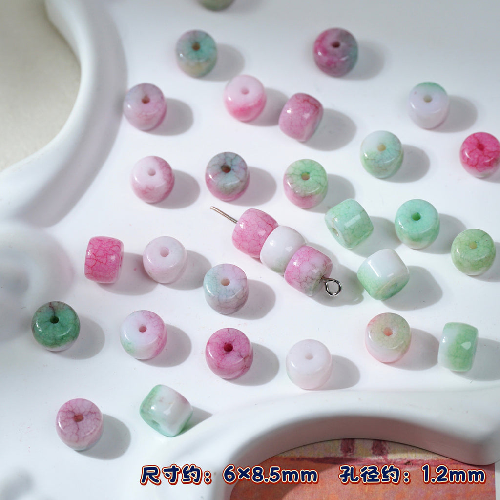 Pink and green marbled round porcelain beads on white tray, one threaded