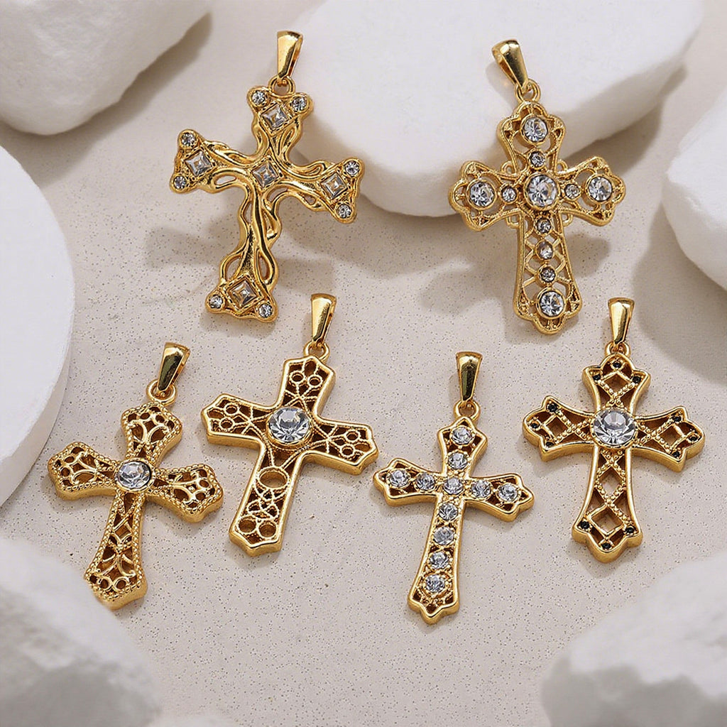 Six gold cross pendants with clear rhinestone accents arranged on a light textured surface