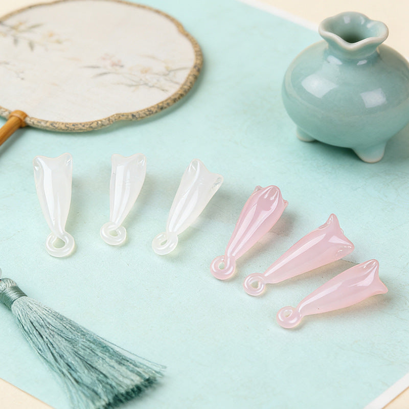 White and pale pink translucent magnolia flower glass pendant beads on aqua surface with paper fan, tassel and celadon vase