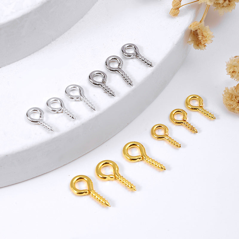 Two rows of small screw eye pin findings on a white display surface