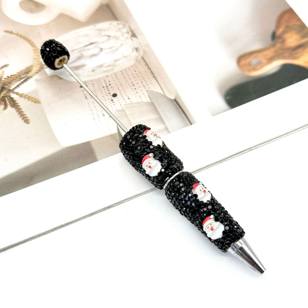 Black rhinestone ballpoint pen with small Santa Claus figures.