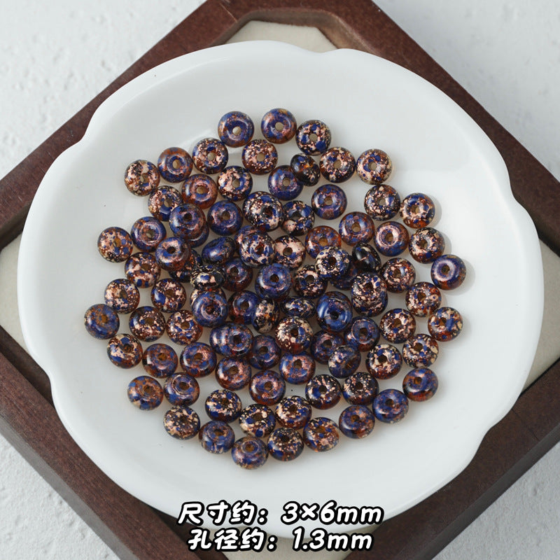 Metallic bronze and dark blue glitter Picasso glass abacus beads piled in a dish.
