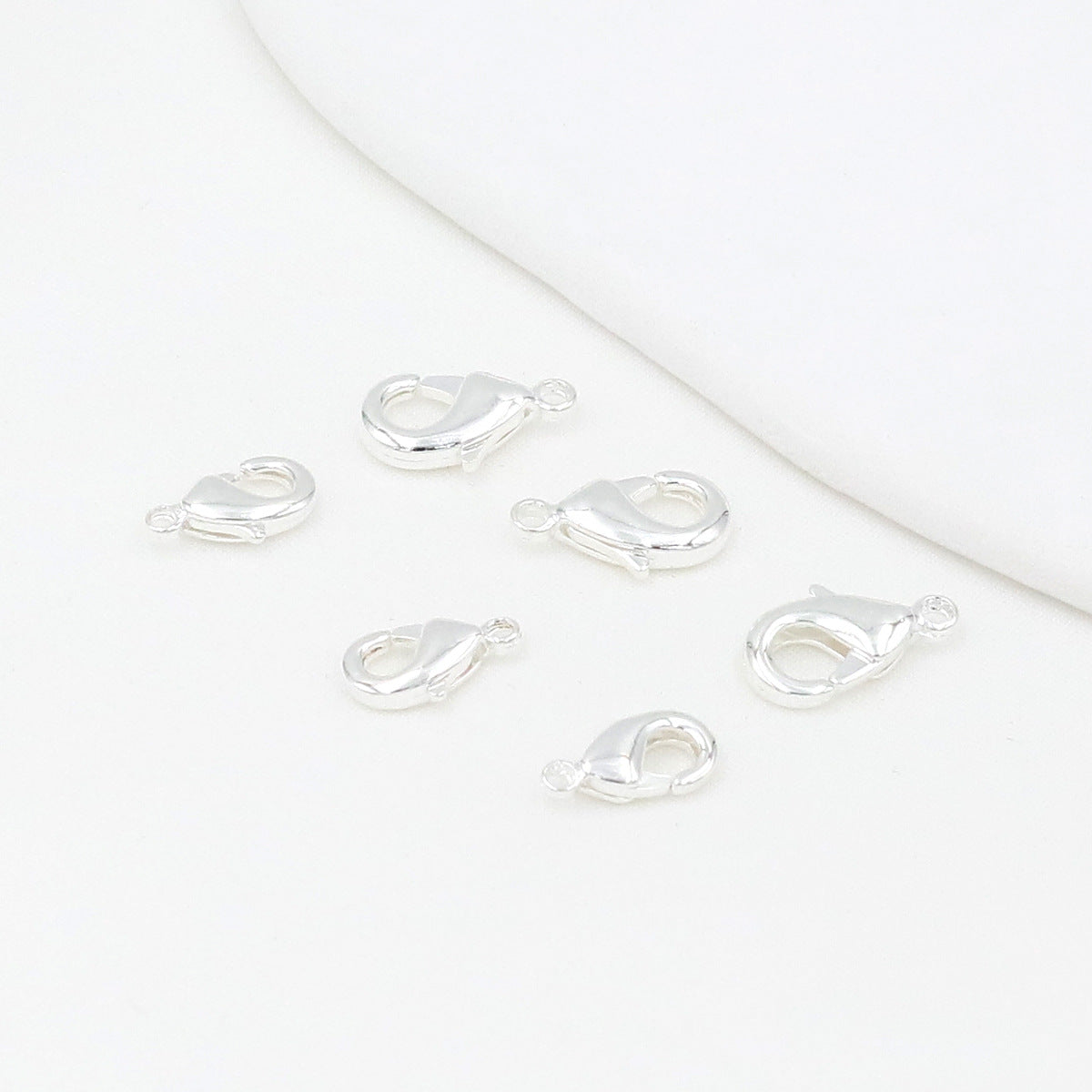Silver teardrop lobster clasps on a white background