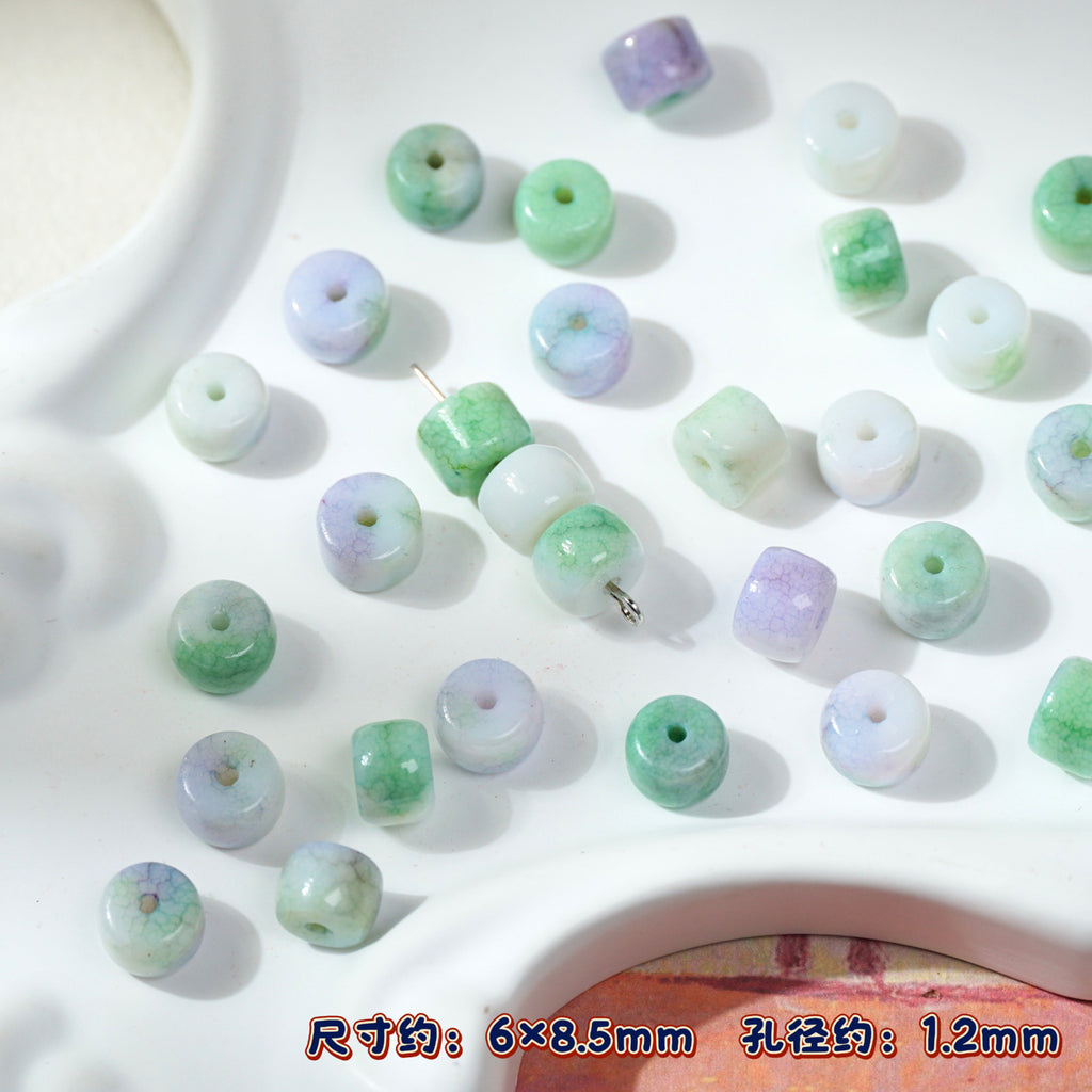 Green and white jadeite cylindrical porcelain beads with holes on white tray