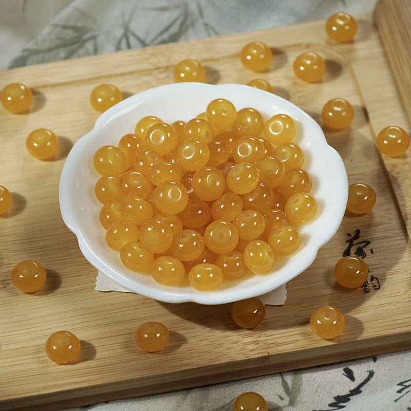 Translucent golden-yellow round beads in a white bowl on a wooden board