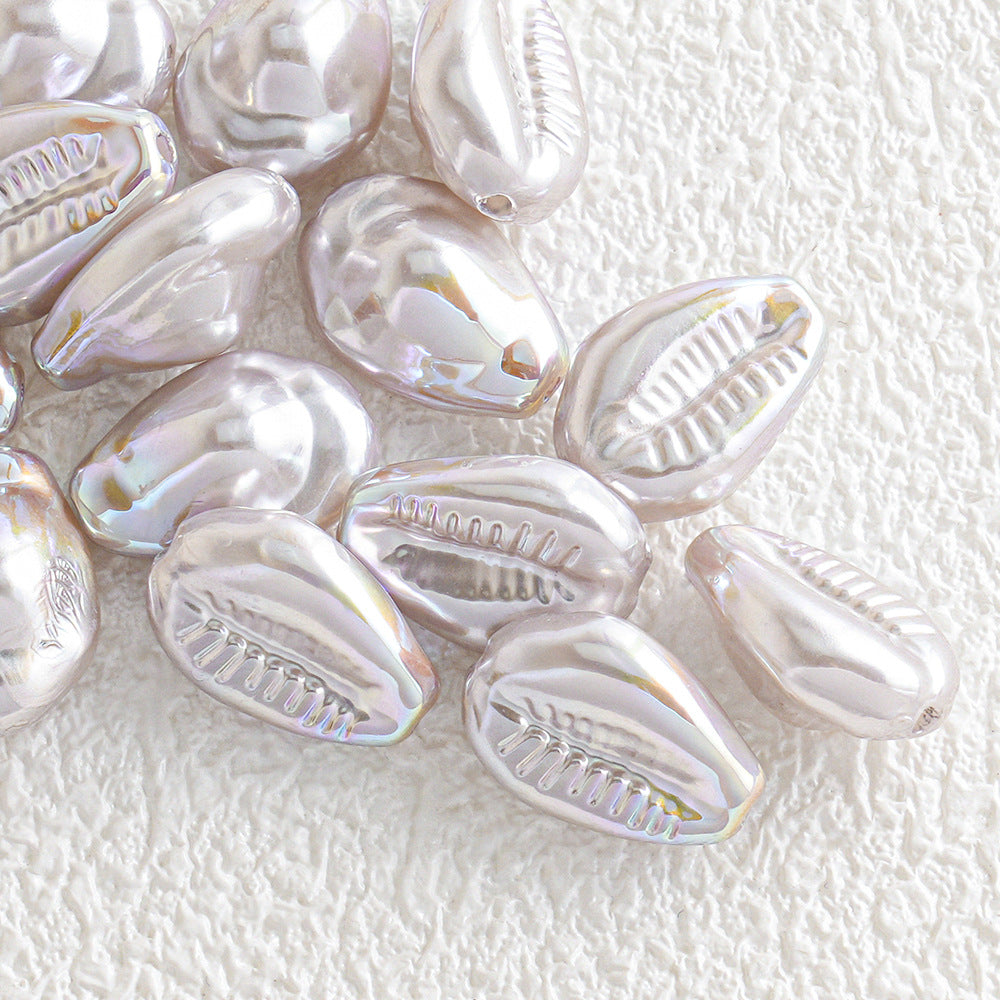 Pile of iridescent cowrie shell beads with a glossy metallic finish on white