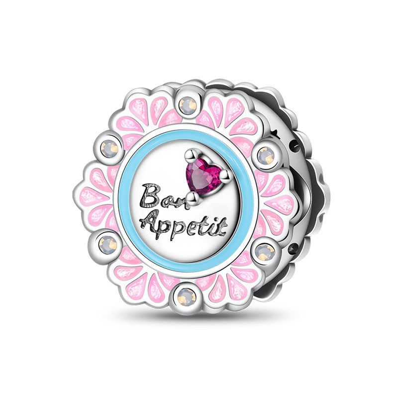 Silver-plated round bead with pink enamel flower petals, blue ring, Bon Appetit text, and pink heart crystal