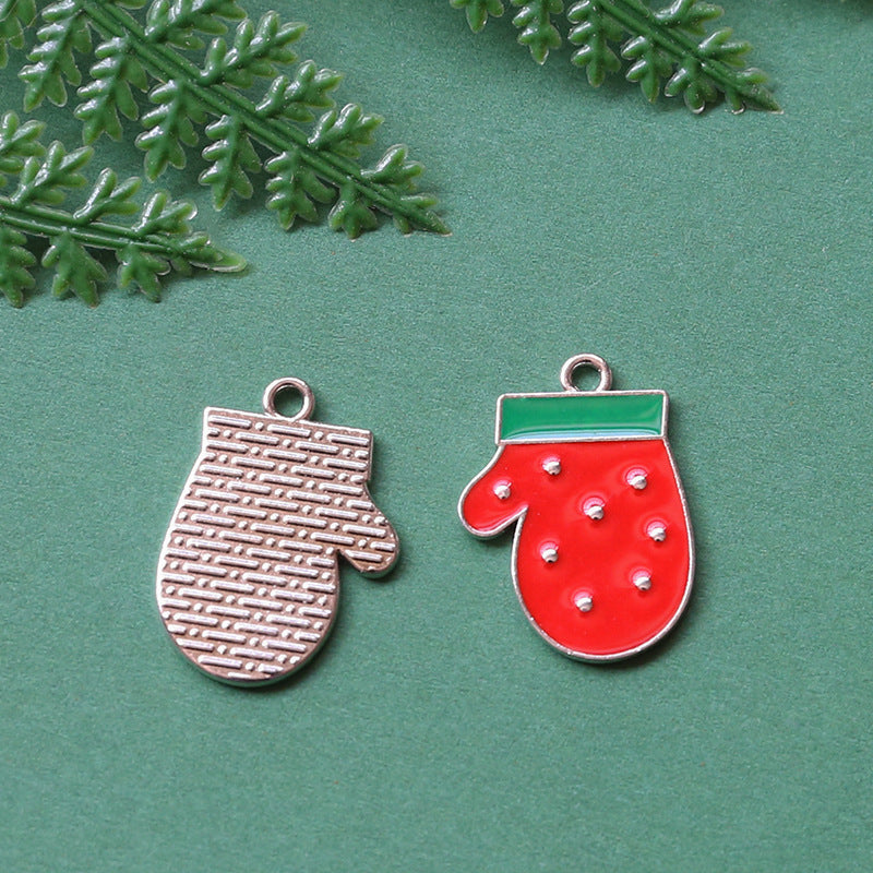 Two Christmas mitten-shaped charms on textured green background with leaves