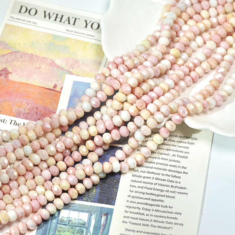 Pink and cream marbled faceted porcelain beads on a ceramic dish and open book