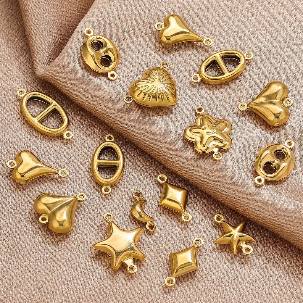 Gold-plated stainless steel double-hole hollow connector charms in assorted shapes on beige fabric