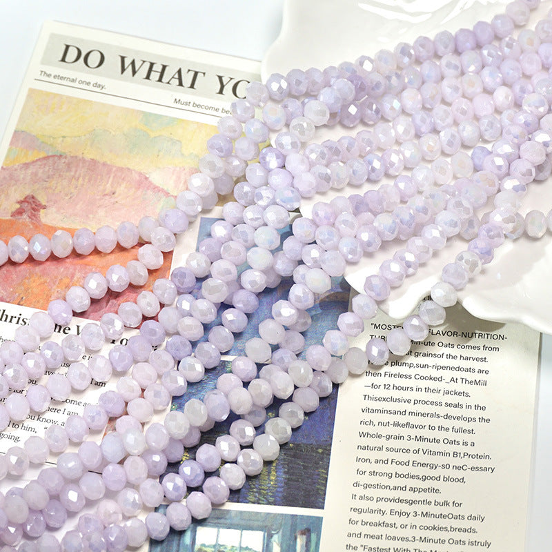Close-up of light purple faceted porcelain bead strands on printed pages
