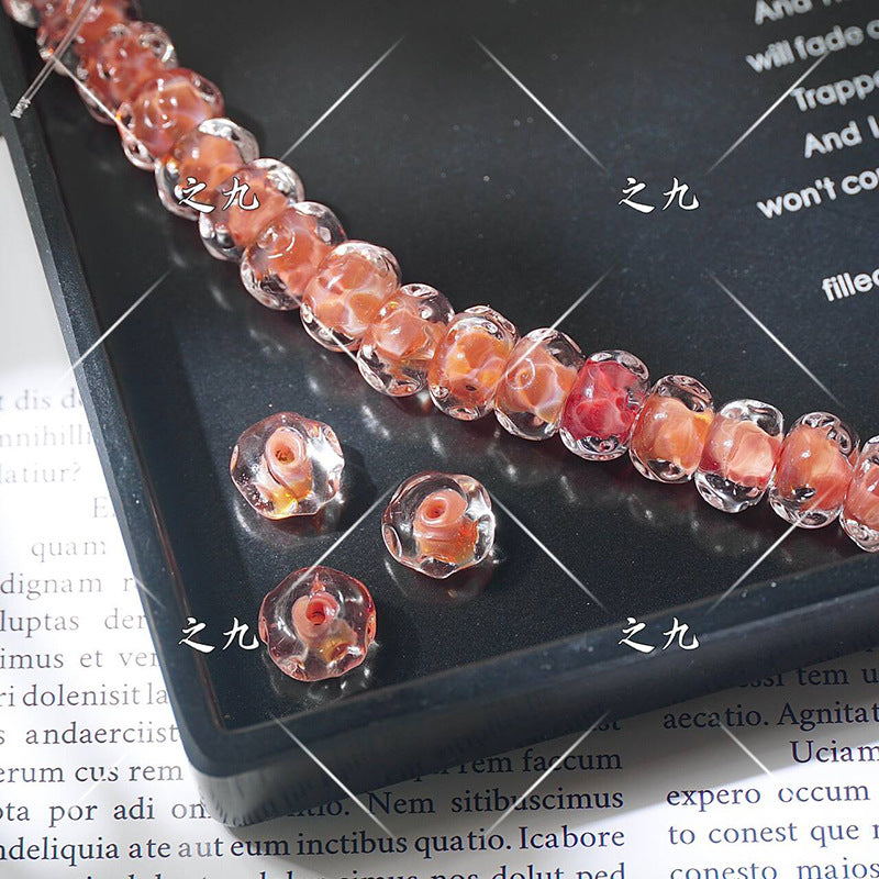 Peach-pink lampwork glass beads with rose swirl centers on a black tray, loose beads