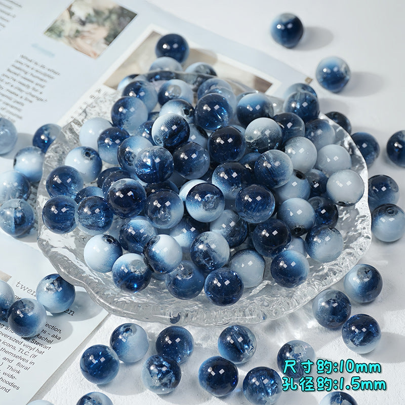 Dark blue and white ice-crackle glass beads piled in a clear textured glass bowl with scattered beads