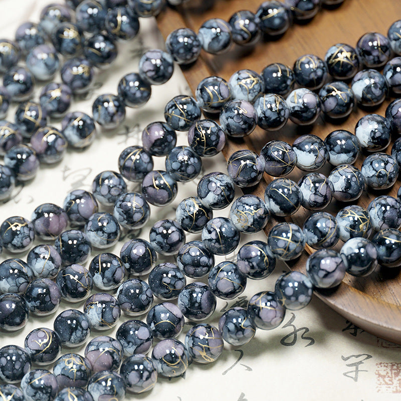 Close-up of dark marbled porcelain bead strands with gold veins on a light surface