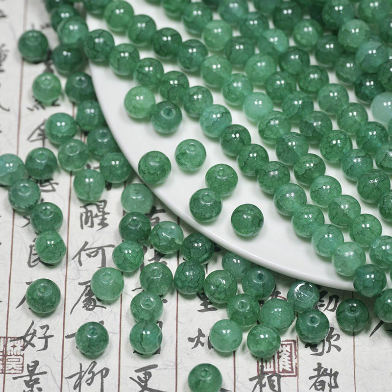 Dark green ice-crackle glass beads arranged on a white plate and calligraphy paper