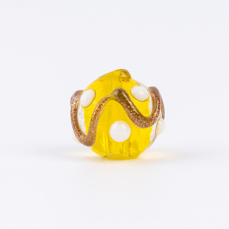 Single yellow gold-sand swirl glass bead with white polka dots and brown glitter