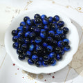 Round glossy cobalt blue and black tiger's eye glass beads in a white bowl