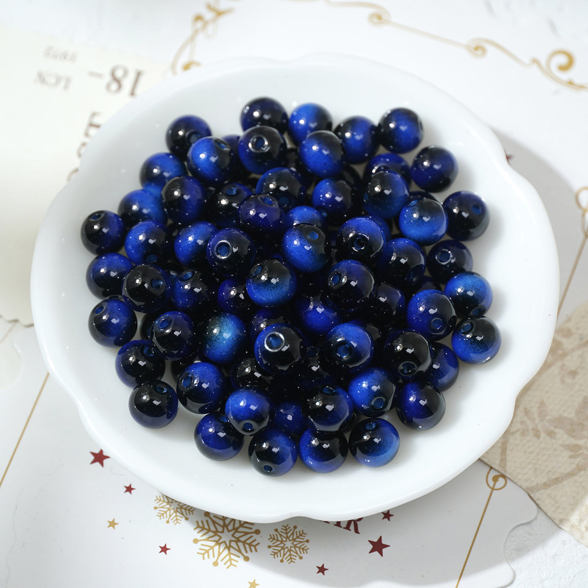 Round glossy cobalt blue and black tiger's eye glass beads in a white bowl
