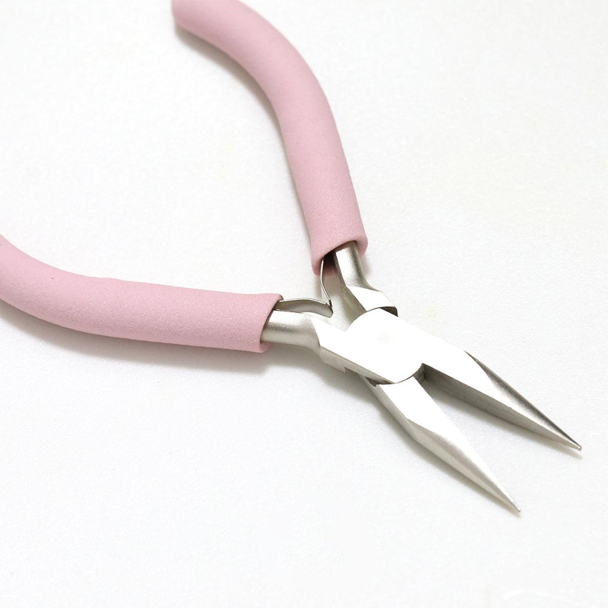 Pink foam-handled needle-nose pliers with silver jaws on white