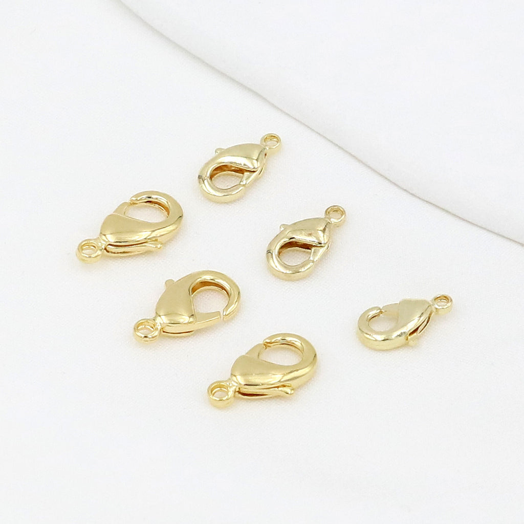 Gold teardrop lobster clasps on a white background