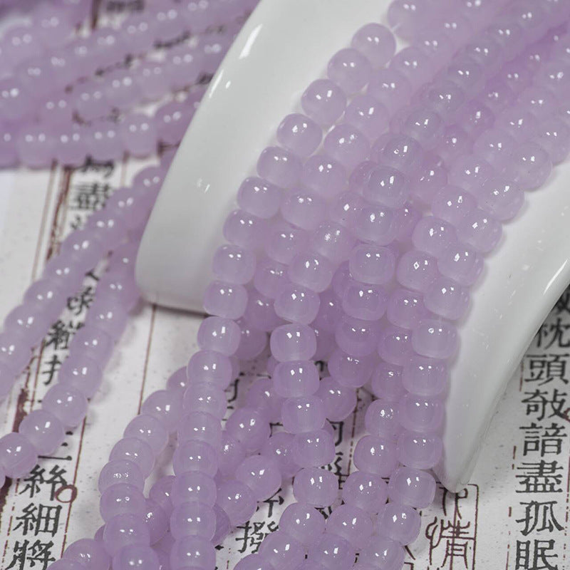 Lavender translucent drum bead strands over a white ceramic dish on printed paper with Chinese characters