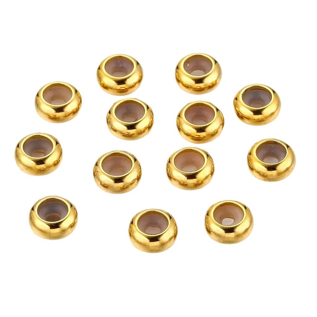 Twelve gold stainless steel flat abacus stopper beads on white, top view showing silicone-lined holes