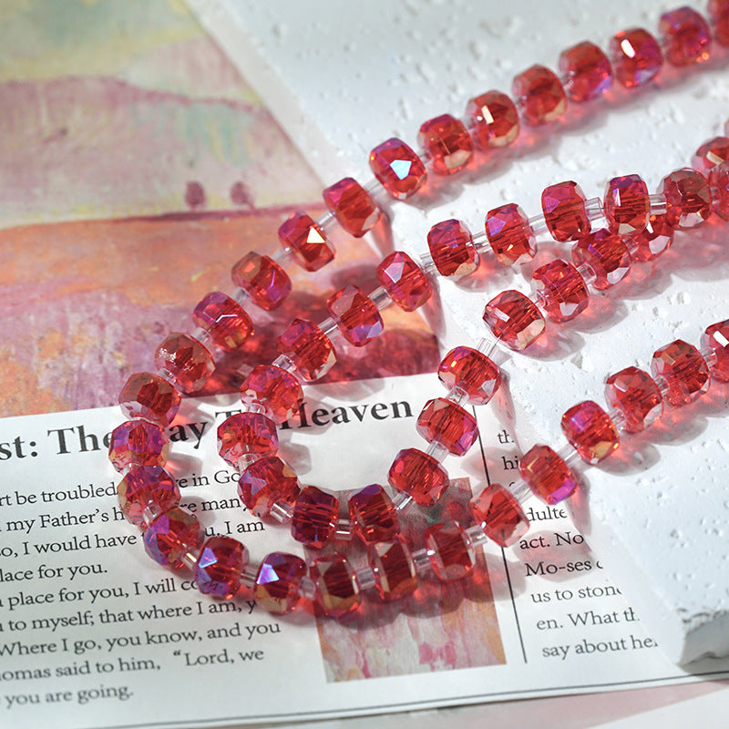 Close-up of faceted red glass beads with an iridescent pink and purple shift arranged on printed book pages