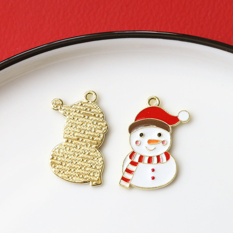 Two Christmas-themed enamel alloy charms on a white plate with red background