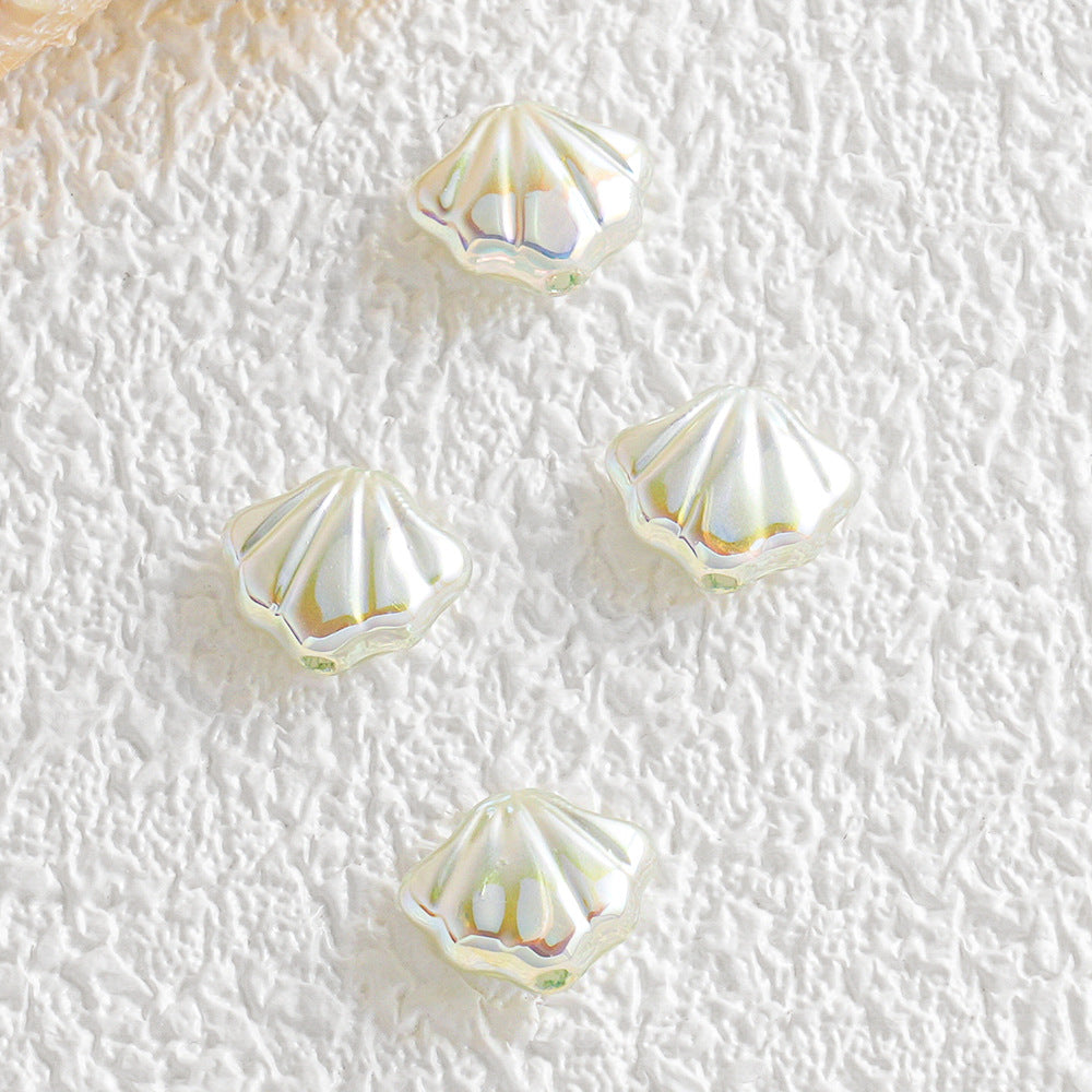 Five small iridescent shell-shaped faux pearl beads on a textured white surface