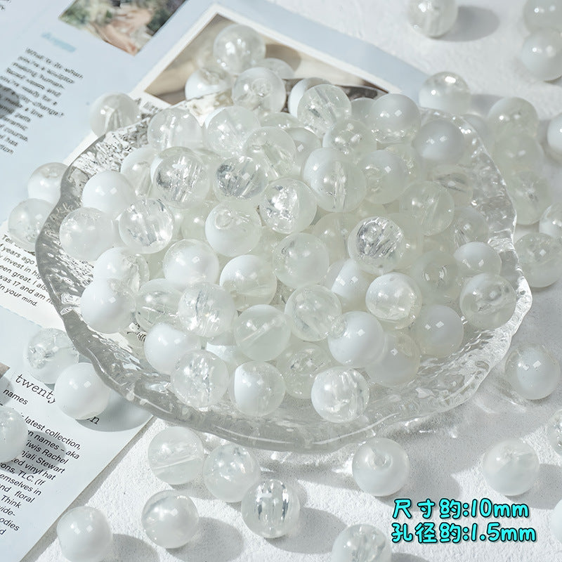 Clear and milky white ice-crackle glass beads piled in a clear textured glass bowl with scattered beads