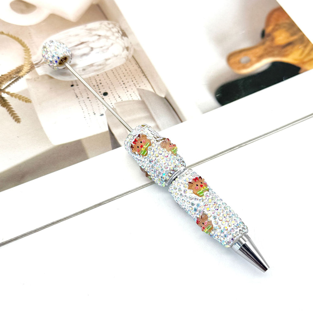 Rhinestone ballpoint pen with colorful cartoon frog charms on a white surface.